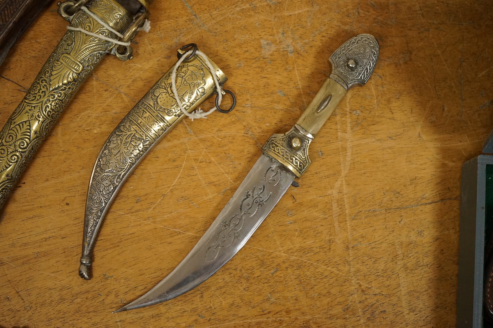 An Indian sword tulwar, the iron hilt with traces of chiselled and inlaid decoration, together with a kukri in its wooden scabbard, a Syrian jambya and a Moroccan jambiya (4)